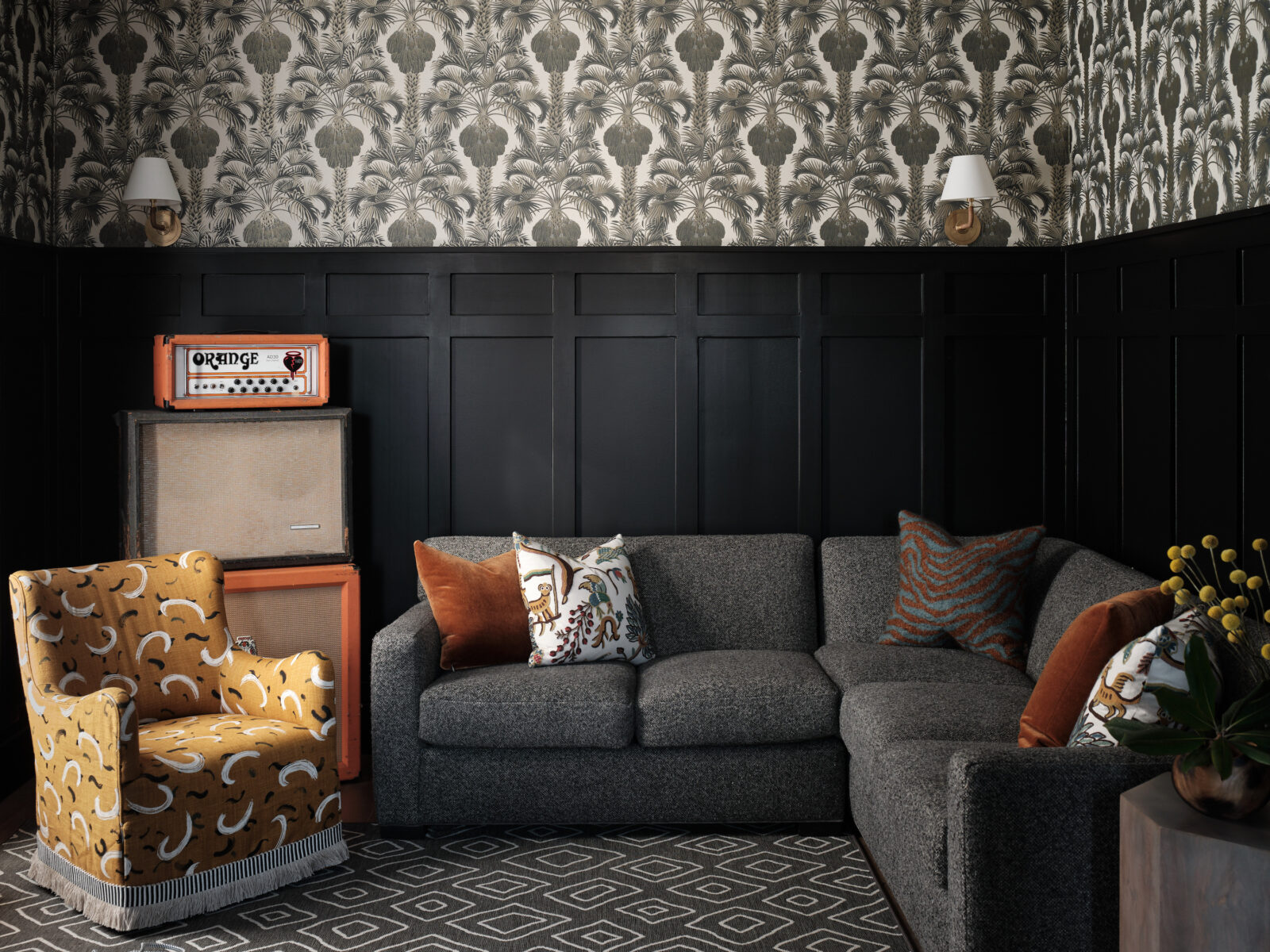 A sitting room with grey and orange furniture and a printed wallpaper