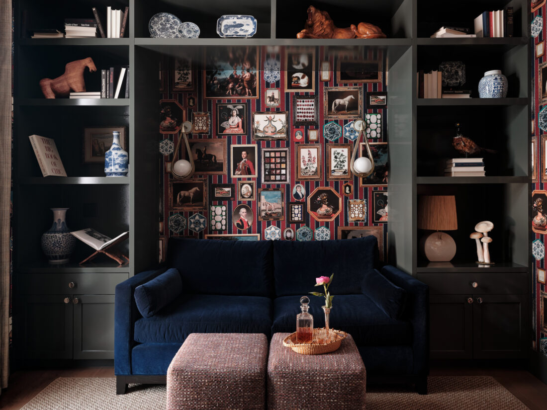 A dark blue velvet couch against a colorful wall of gallery-hung artwork