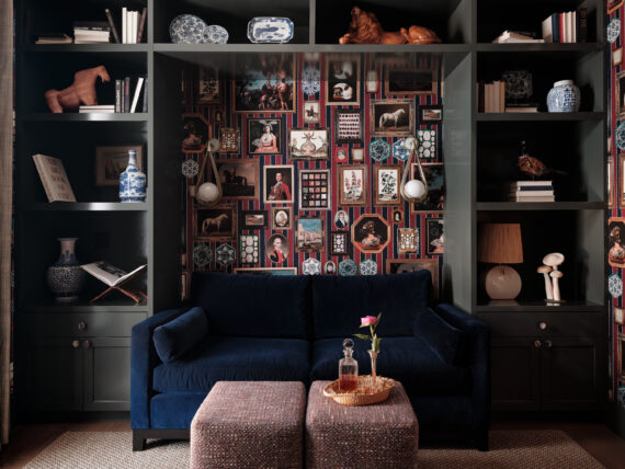 A dark blue velvet couch against a colorful wall of gallery-hung artwork