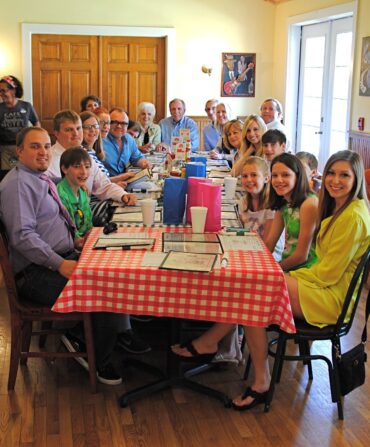 A family sits in a restaurant at a checked red and white table.