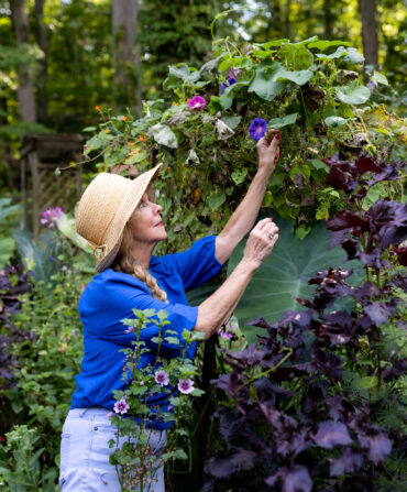 A woman reaches for flowers in a garden