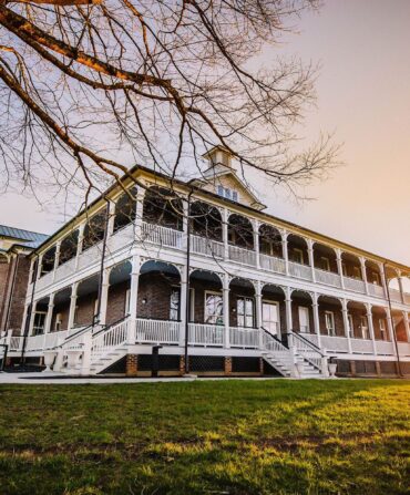 A large stately building with double-porches sits on a hill