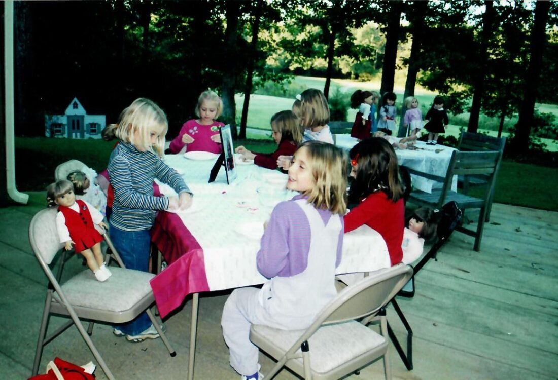 Little girls and dolls at tables