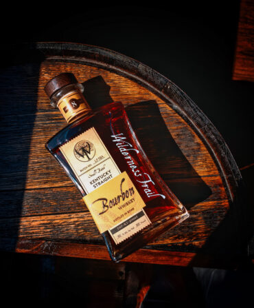 A bottle of bourbon on a wood barrel