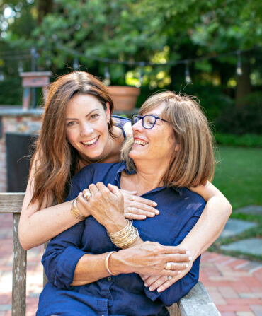 A portrait of two women hugging on a bench