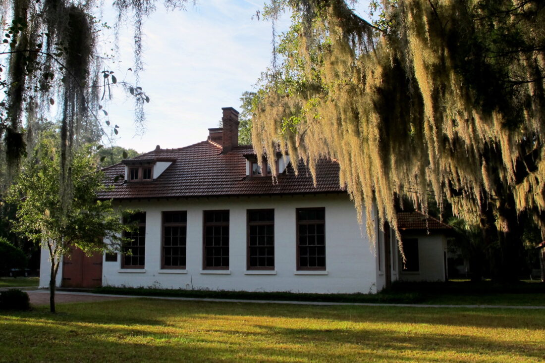 A white building under live oak trees