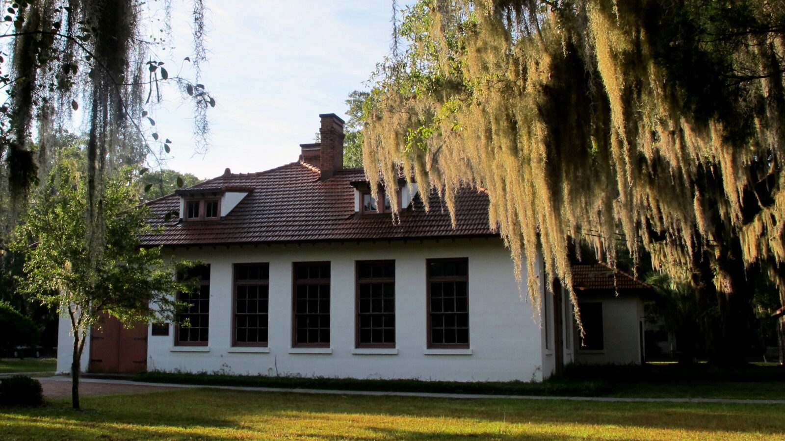 A white building under live oak trees