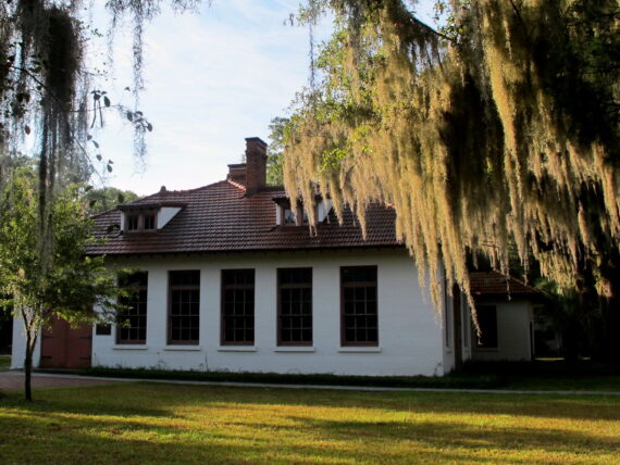 A white building under live oak trees