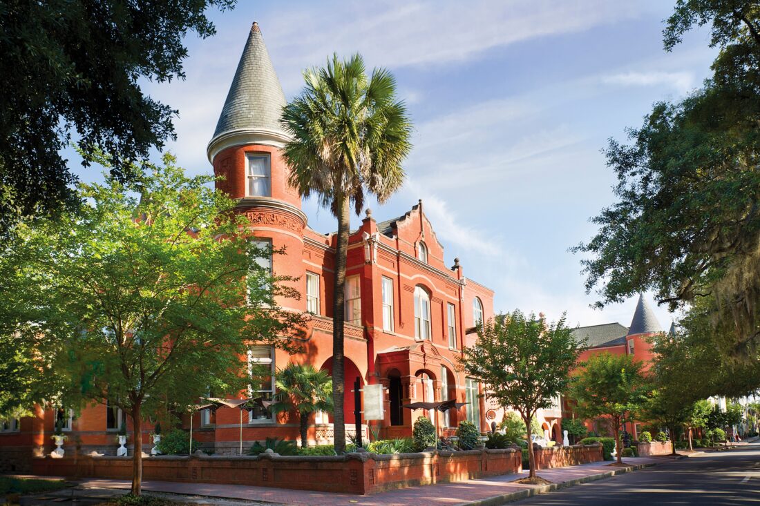 A stately brick building in a tree-covered street