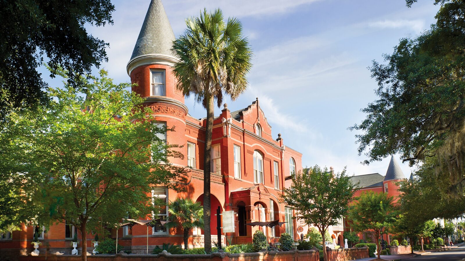 A stately brick building in a tree-covered street