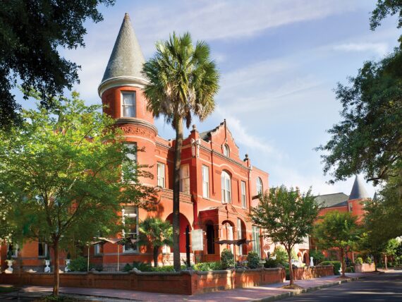 A stately brick building in a tree-covered street