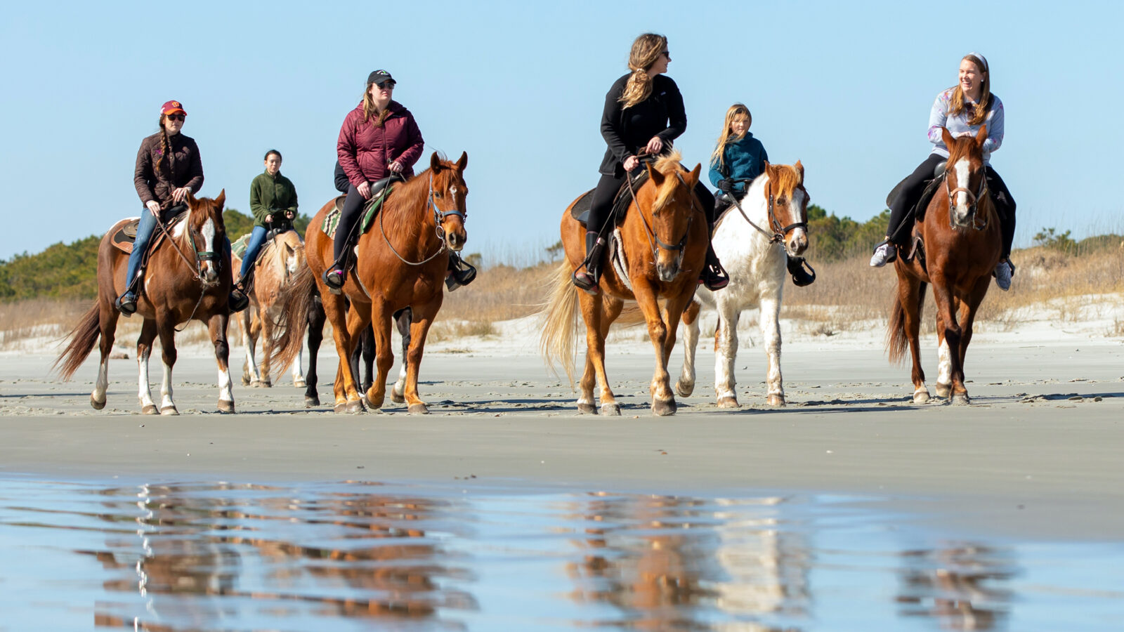 People ride horses on the beach