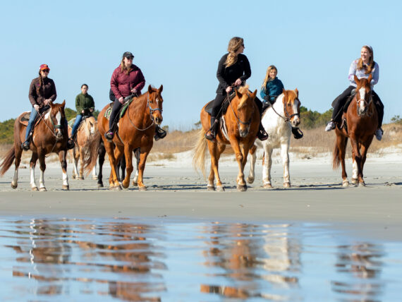 People ride horses on the beach