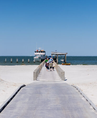 People walk on a beach to a ferry
