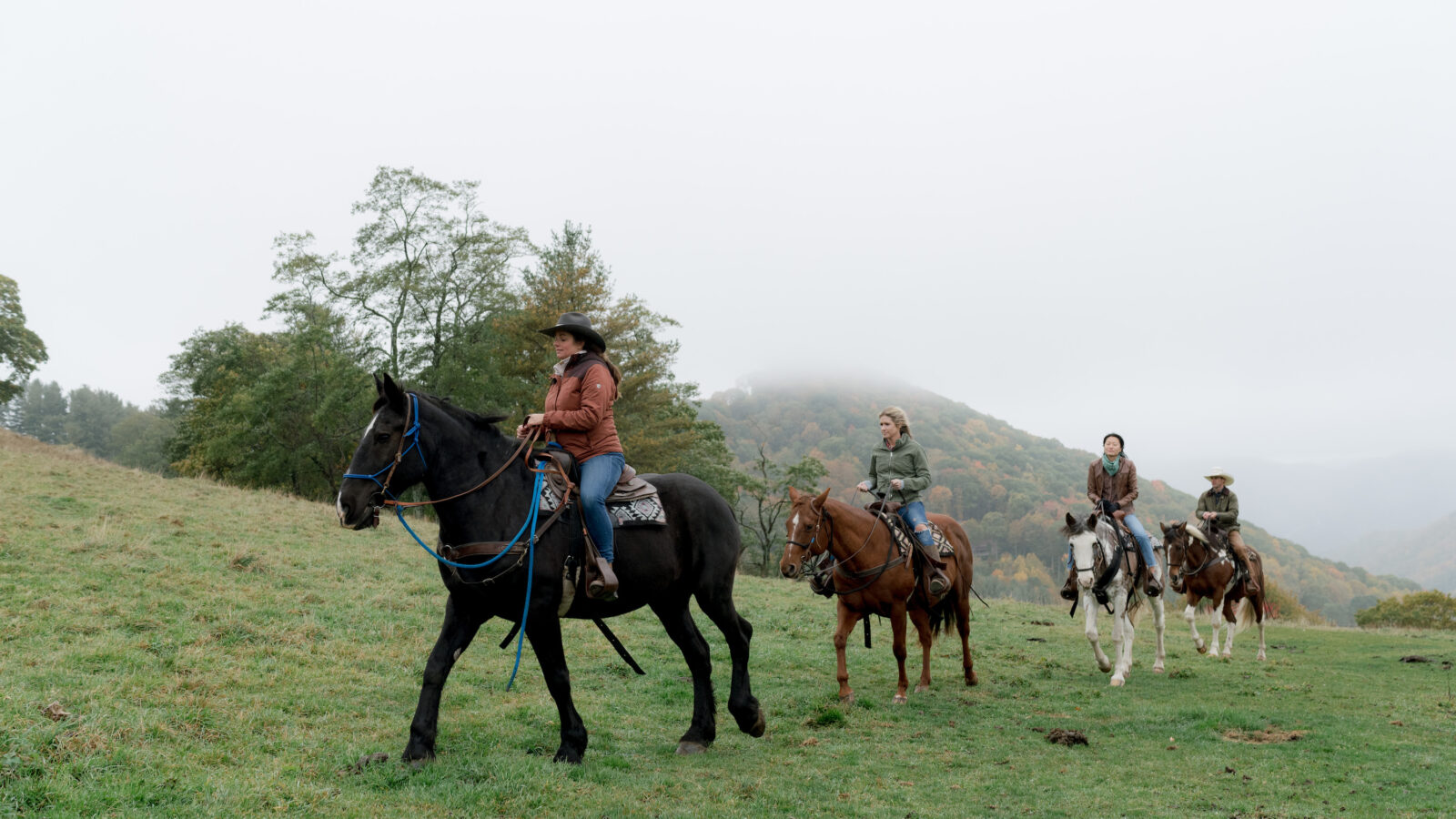People ride horses through the mountains