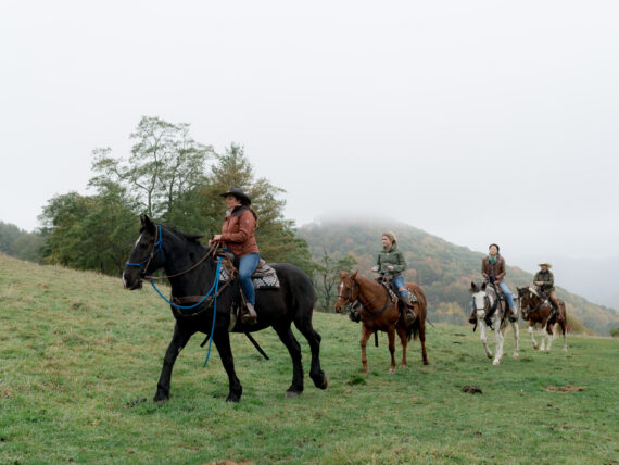 People ride horses through the mountains