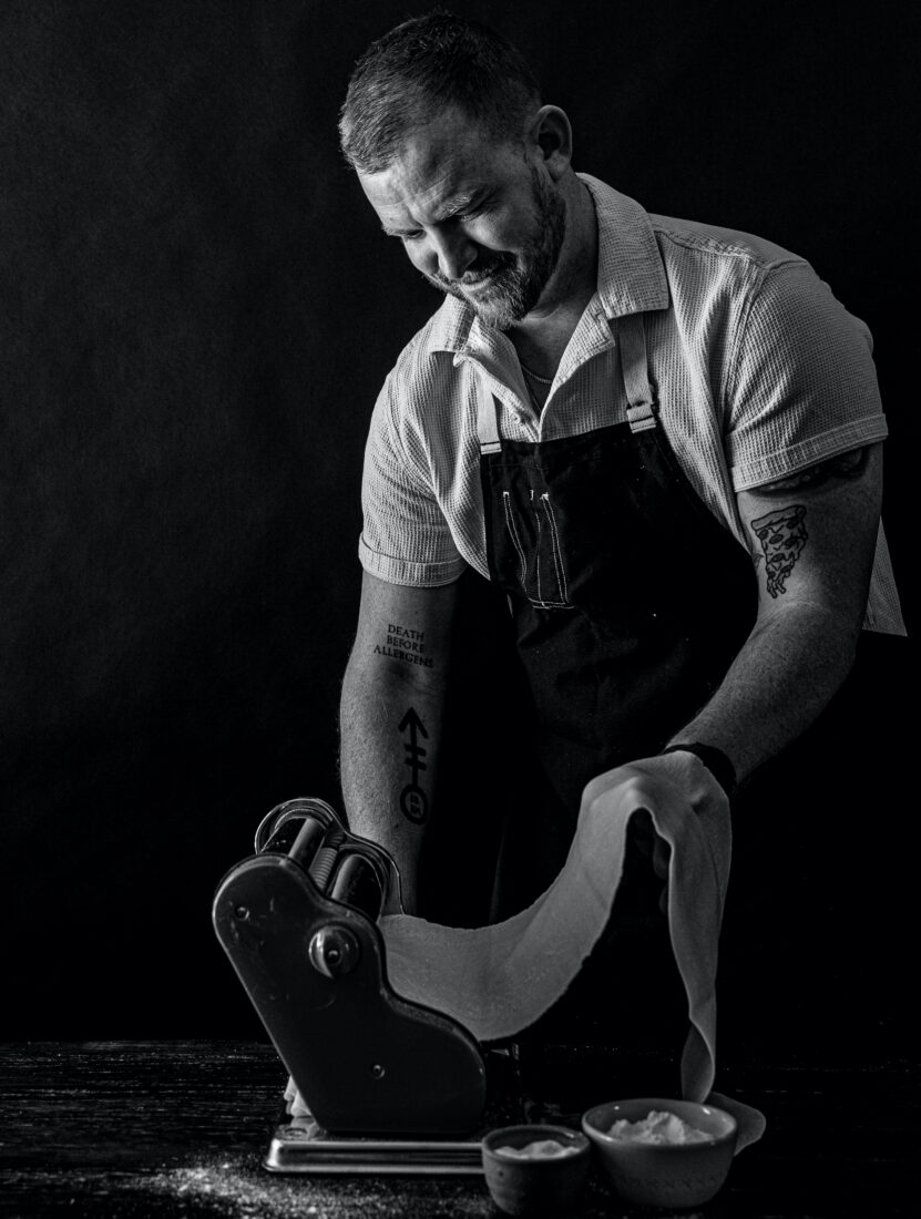 A man pulls pasta through a machine