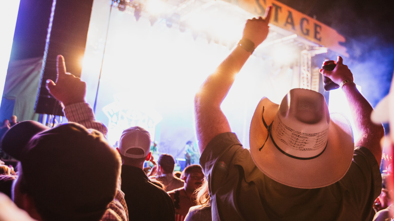 A crowd of people listen to music in front of a concert stage