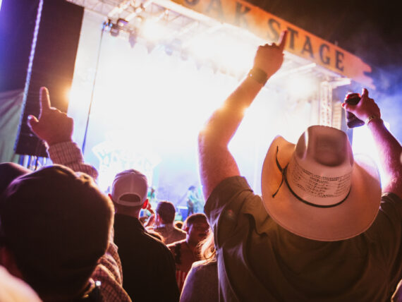 A crowd of people listen to music in front of a concert stage