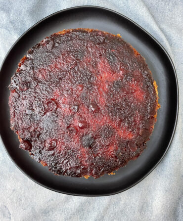 A round red cake on a black plate, seen from above