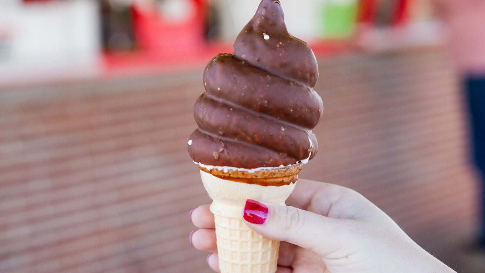 A hand holds a chocolate-dipped ice cream cone
