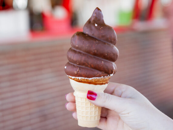A hand holds a chocolate-dipped ice cream cone