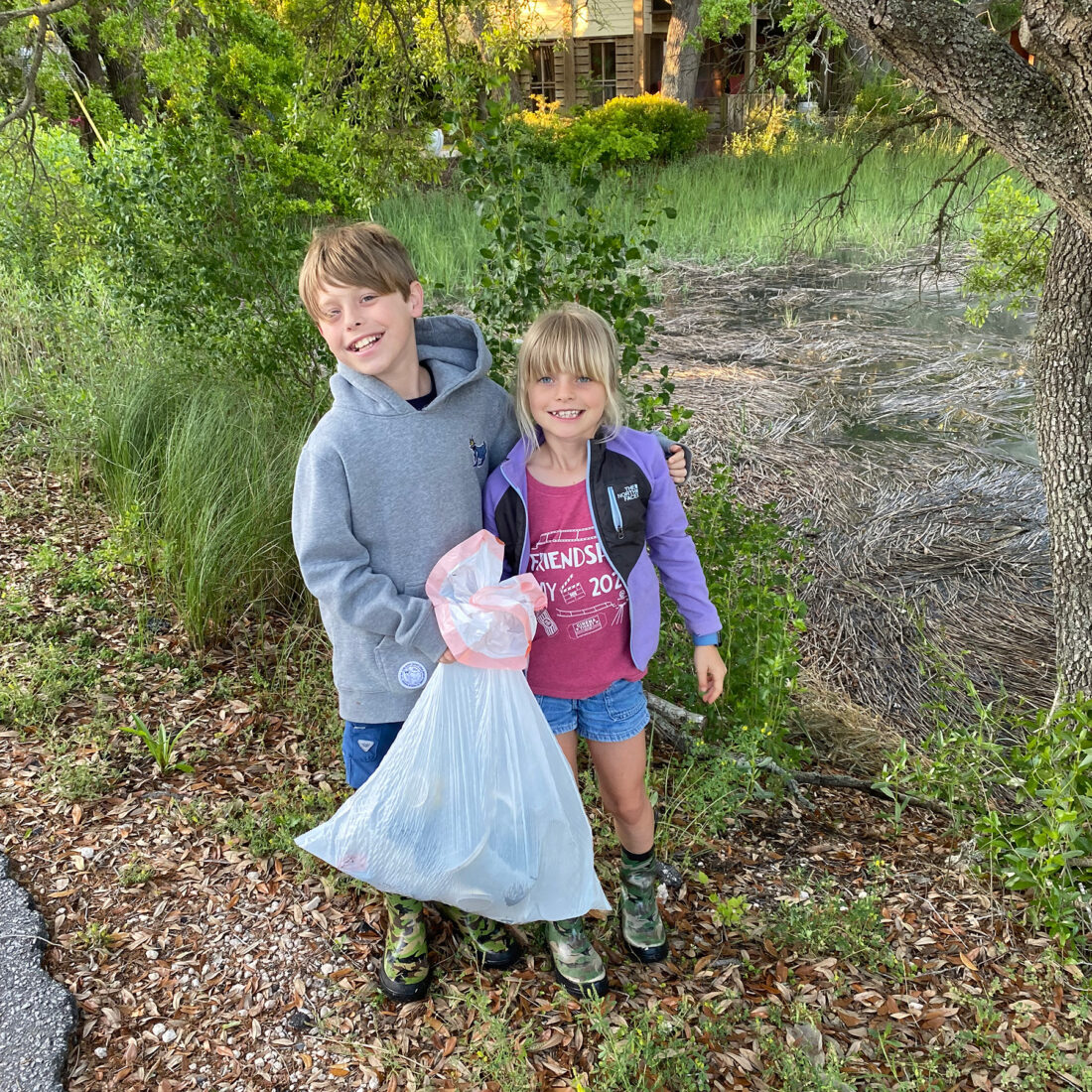 Two kids holding a trash bag