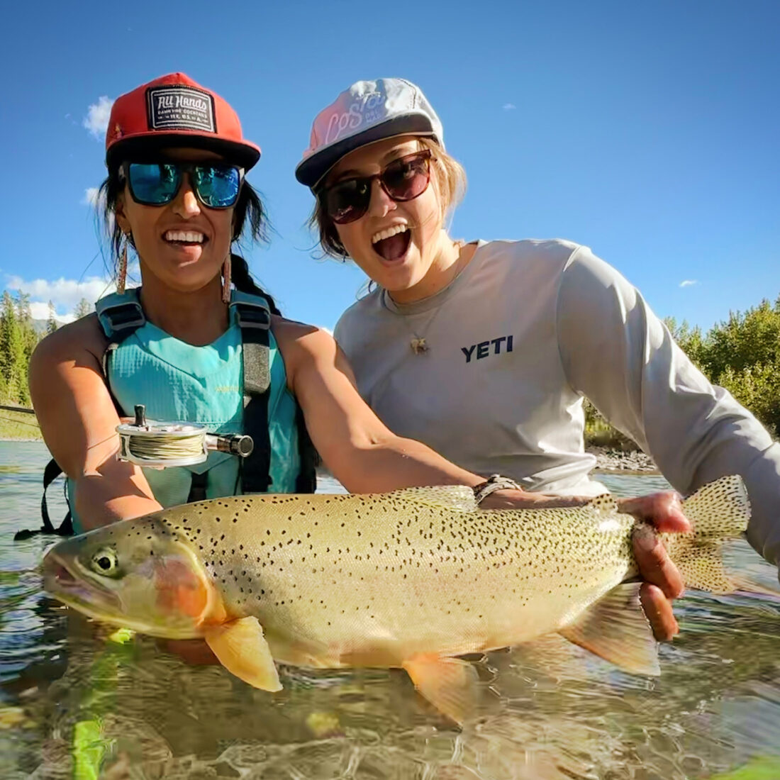 Two women in a river holding a fish