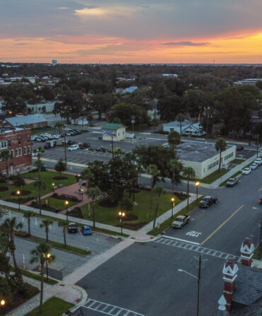 An aerial view of a small town with red brick buildings and large grassy parks.