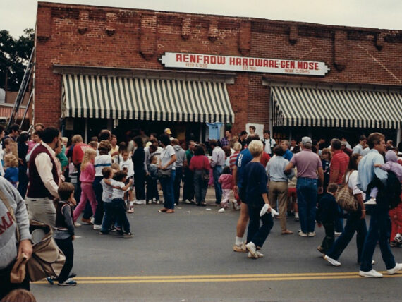 A vintage photo of a hardware storefront with a crowd of people in front of it