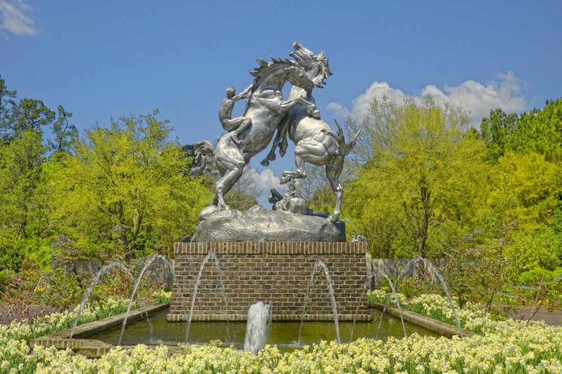 A sculpture of two horses fighting in a garden