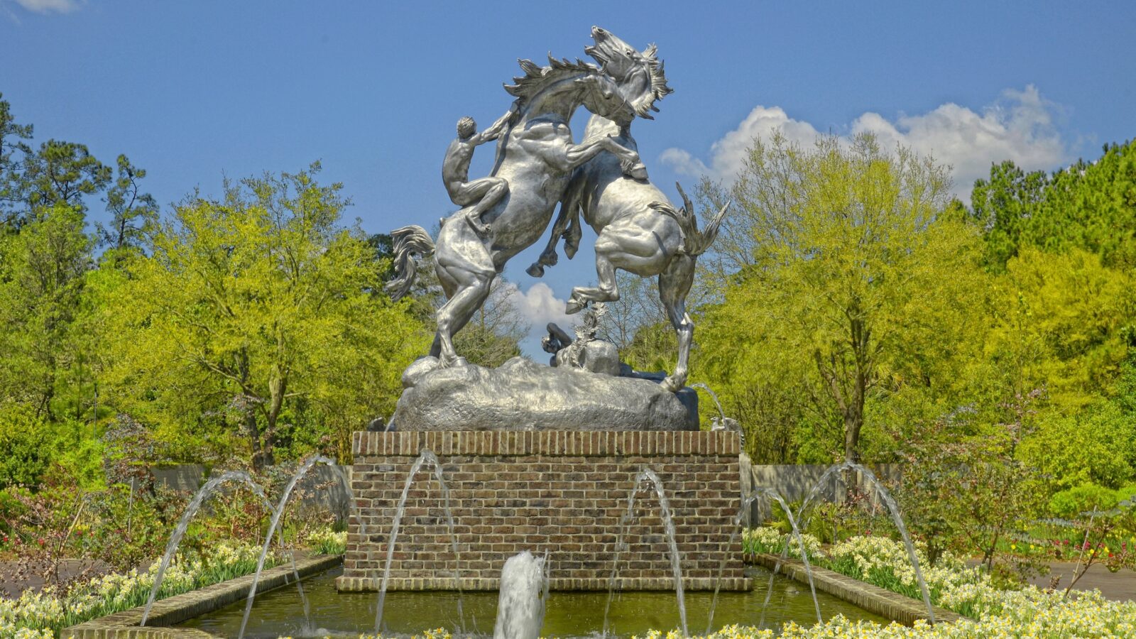 A sculpture of two horses fighting in a garden