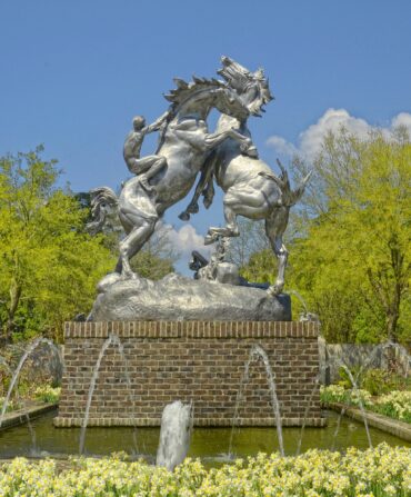 A sculpture of two horses fighting in a garden