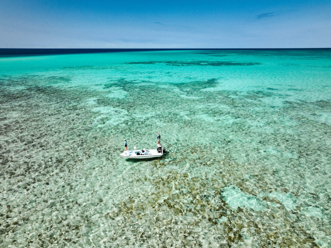 People fish on a boat on a flat in blue water