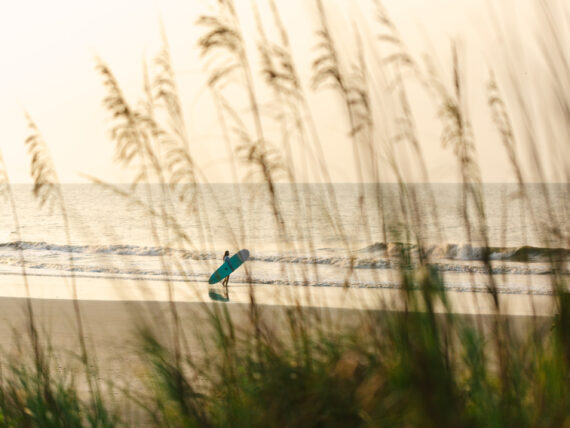 A surfer heads out to the water on a beach