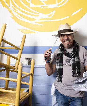 A man stands in a restaurant with stacked chairs on tables