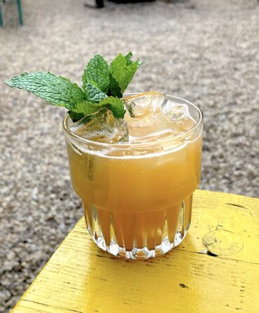 An orange cocktail in a glass with mint