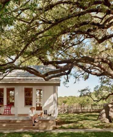 A man and dog sit on a porch of a house