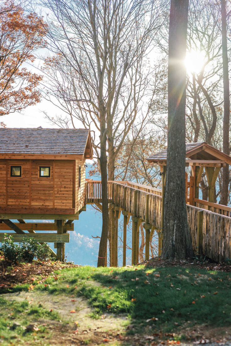 A cabin sits on the edge of a mountain and overlooks a valley