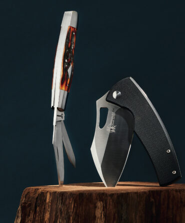 Two pocket knives stuck into a tree stump on a navy background