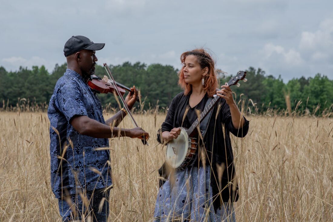 A man playing the fiddle beside a woman playing the banjo