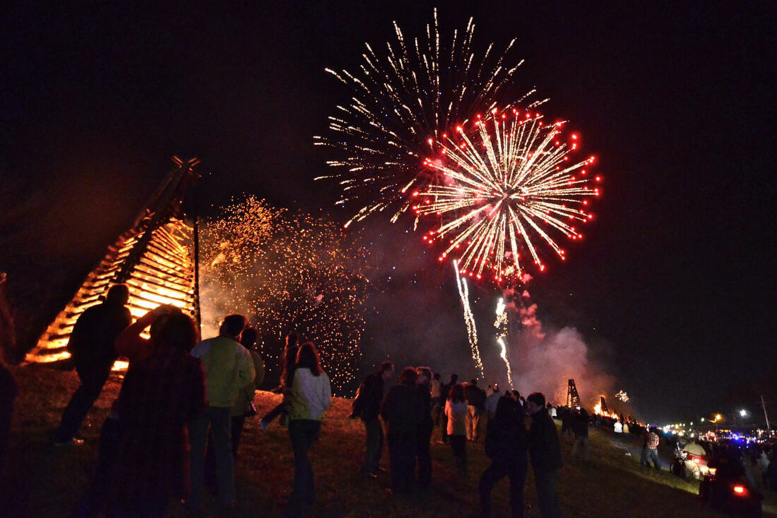 Fireworks light up the sky over bonfires