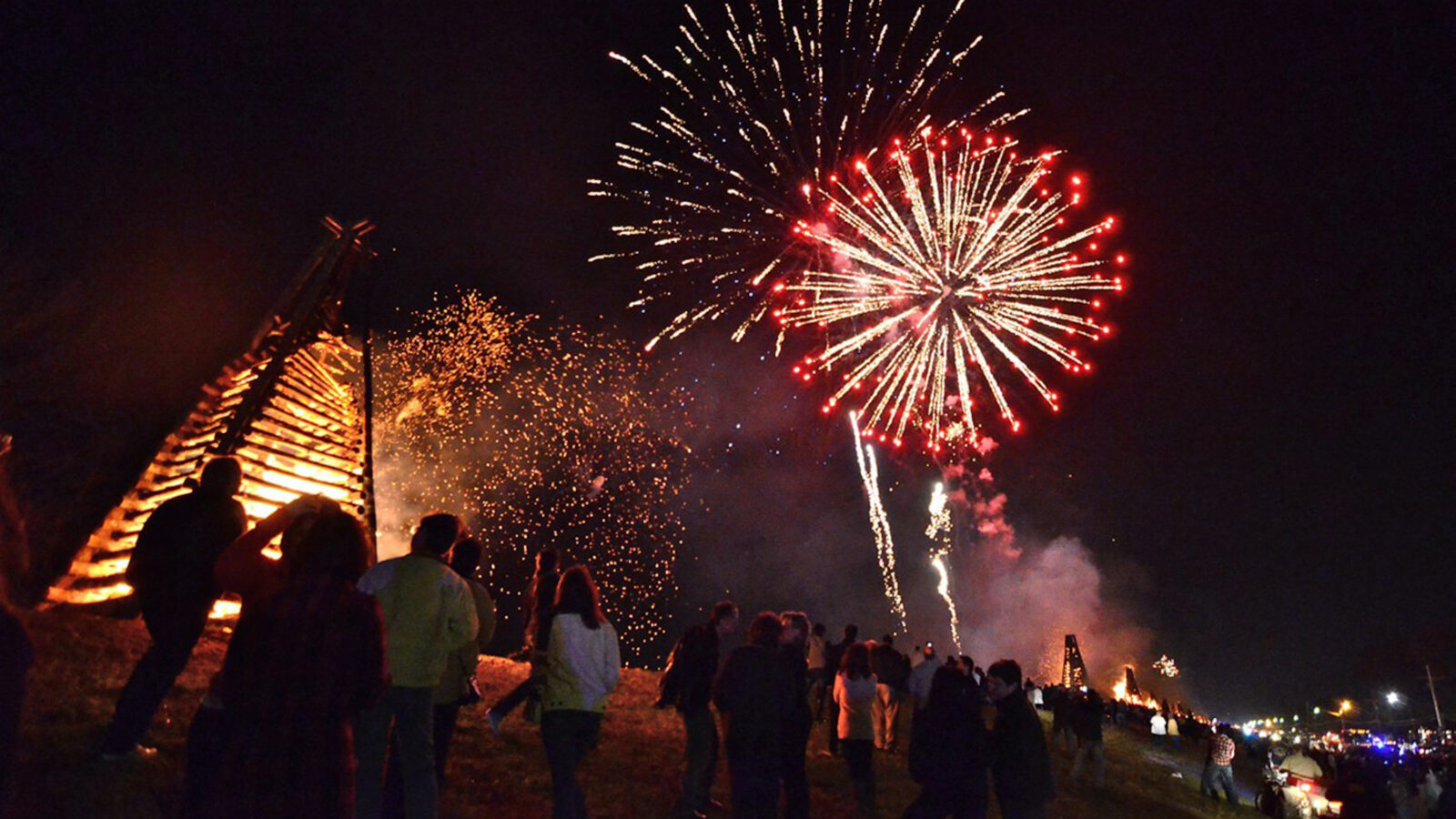 Fireworks light up the sky over bonfires