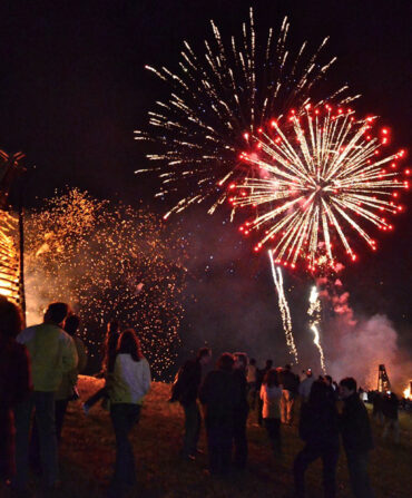 Fireworks light up the sky over bonfires