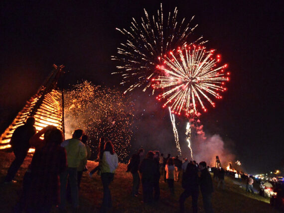 Fireworks light up the sky over bonfires