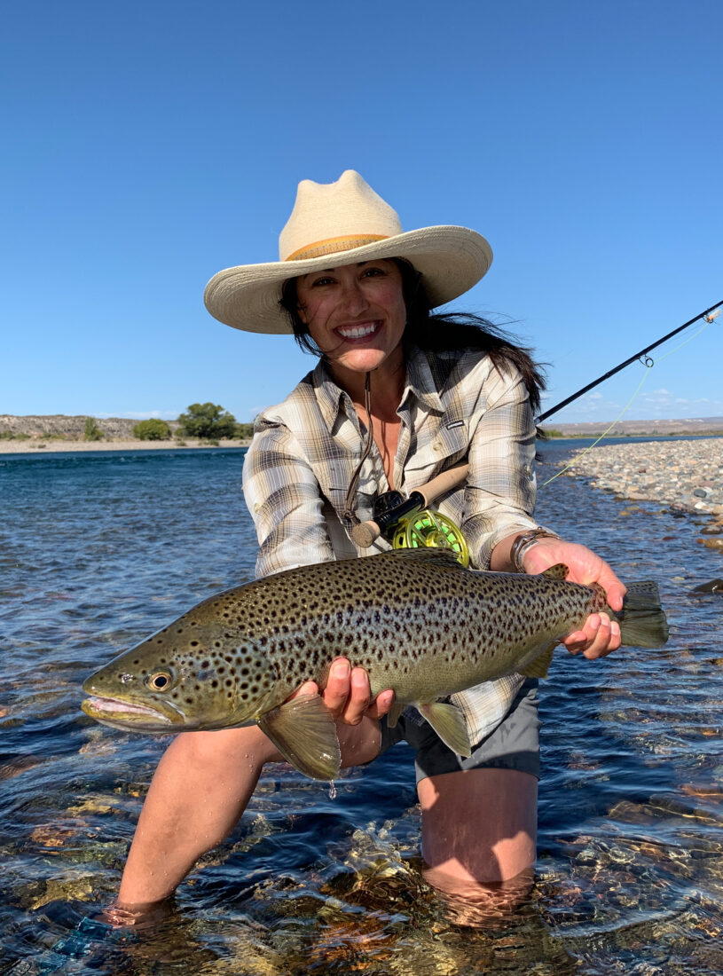A woman in a river holding a fish