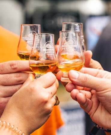 People hold bourbon glasses
