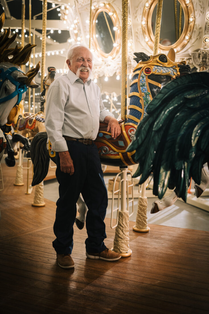 A man stands by a carousel