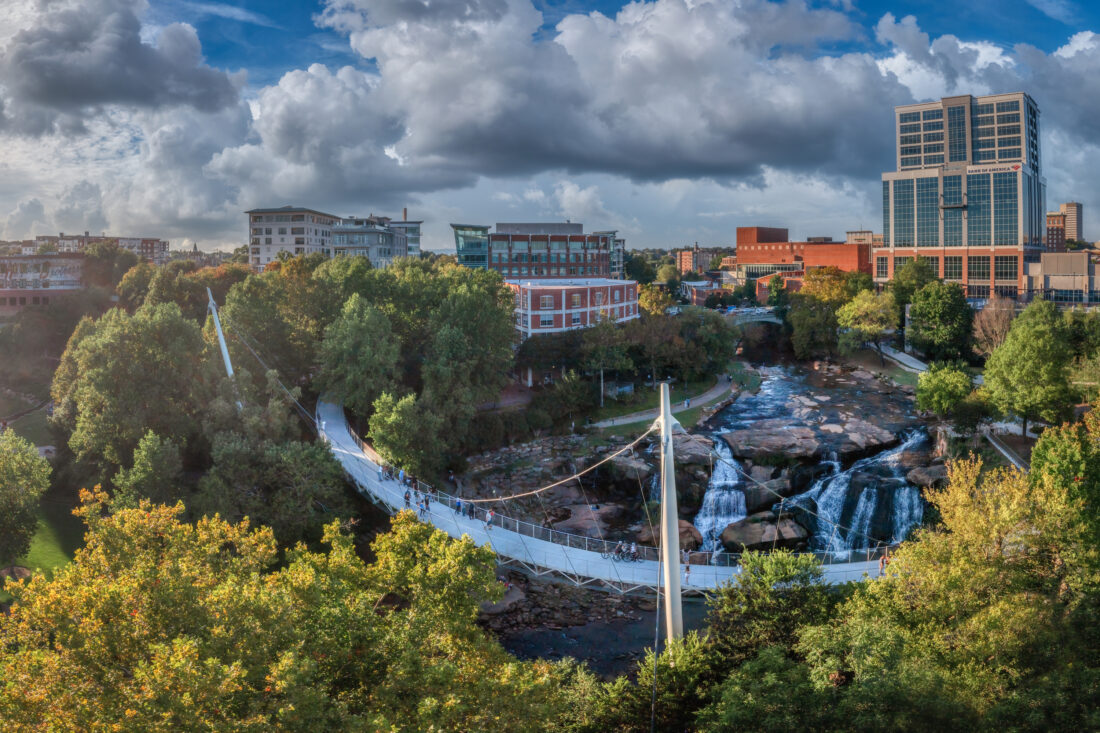 A bridge sweeps over a river before a cityscape
