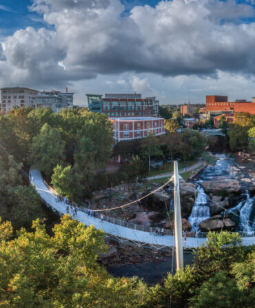 A bridge sweeps over a river before a cityscape